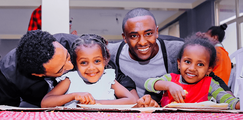Two fathers and their daughters pose for a photo.