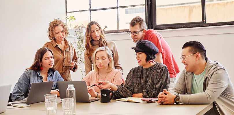 Group of marketers having a meeting around a laptop