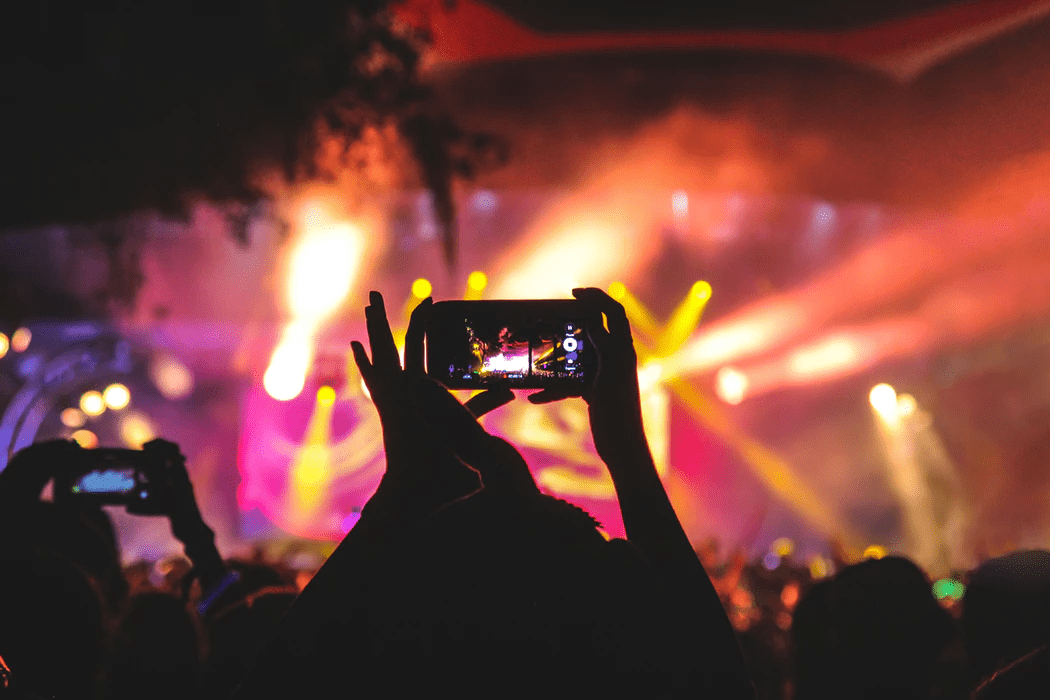 Person recording a concert with her phone in a crowd