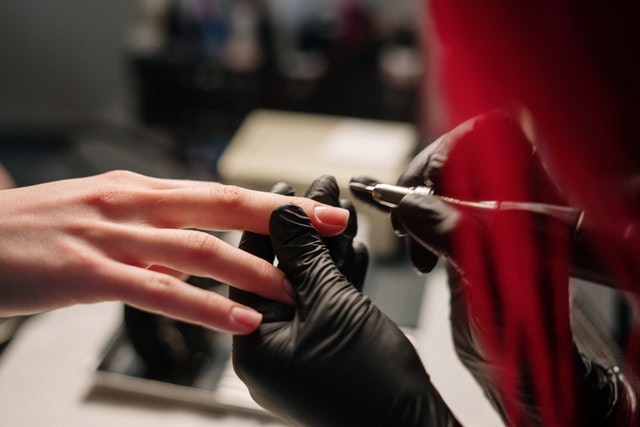 Woman providing nail treatment to its customer in a salon