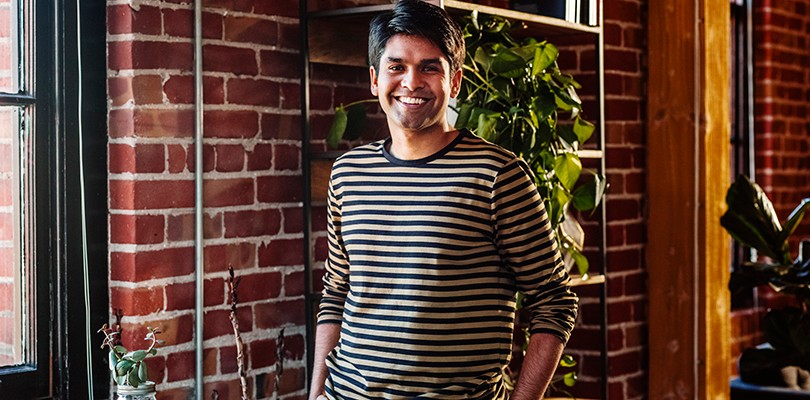 A portrait of a man standing and smiling looking at camera.