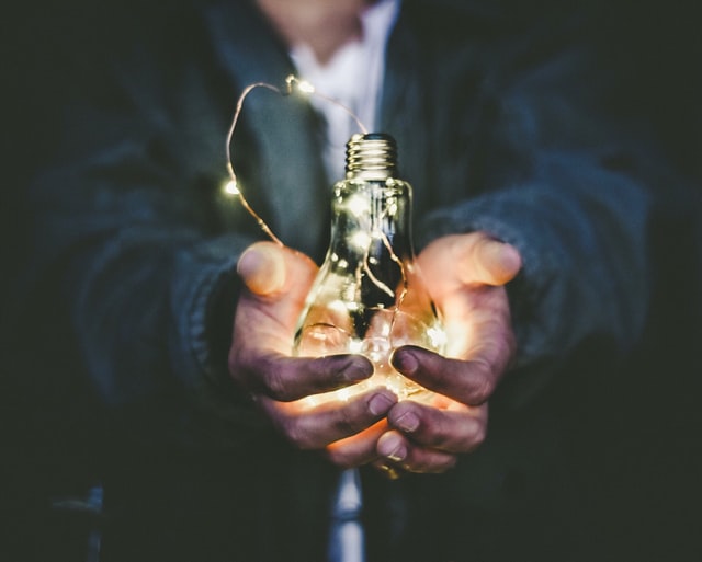 A man holding a light bulb in his palms.