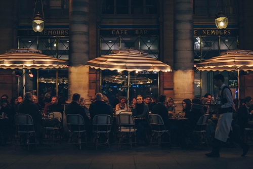 patrons eating outdoors in front of a cafe at night