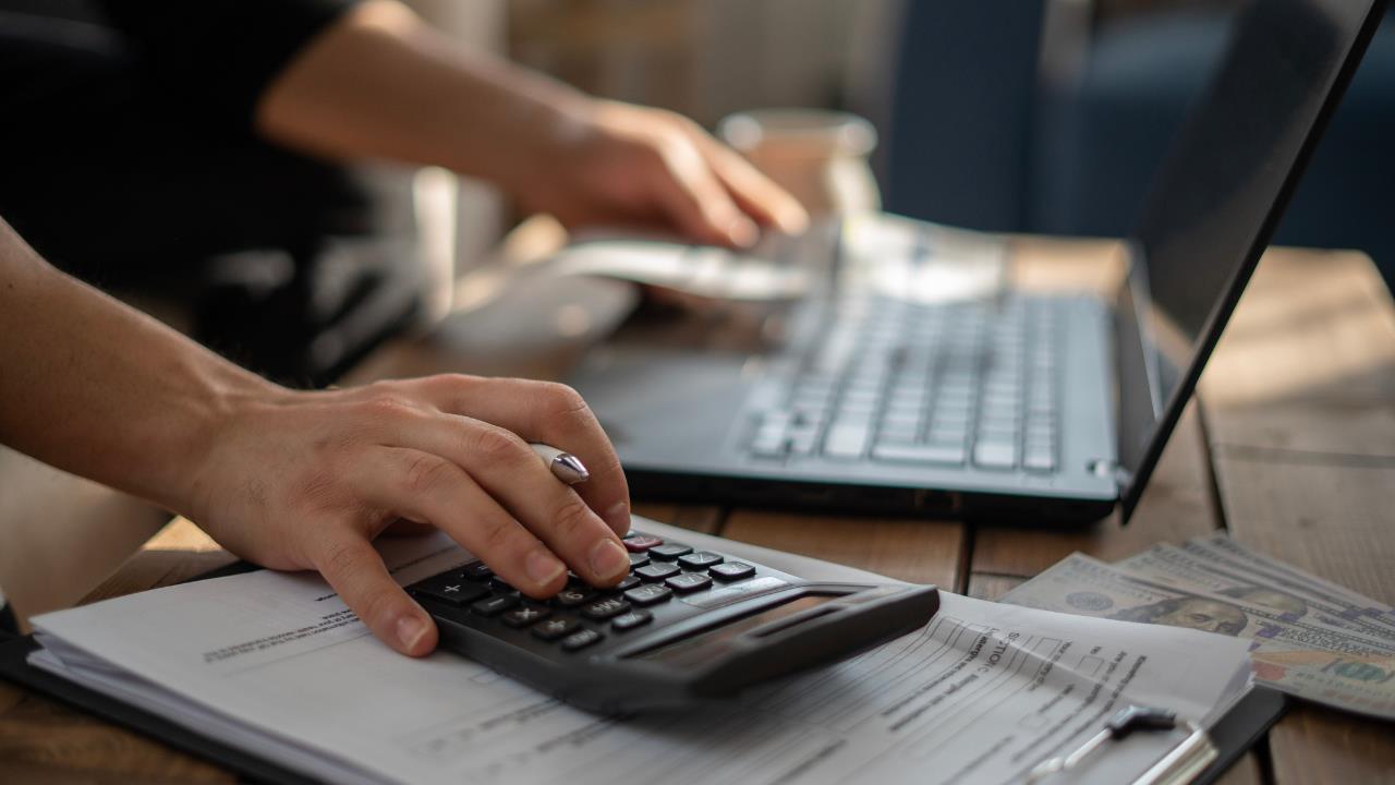 How to start a farm - Cost to start a farm, person calculating costs and using a PC