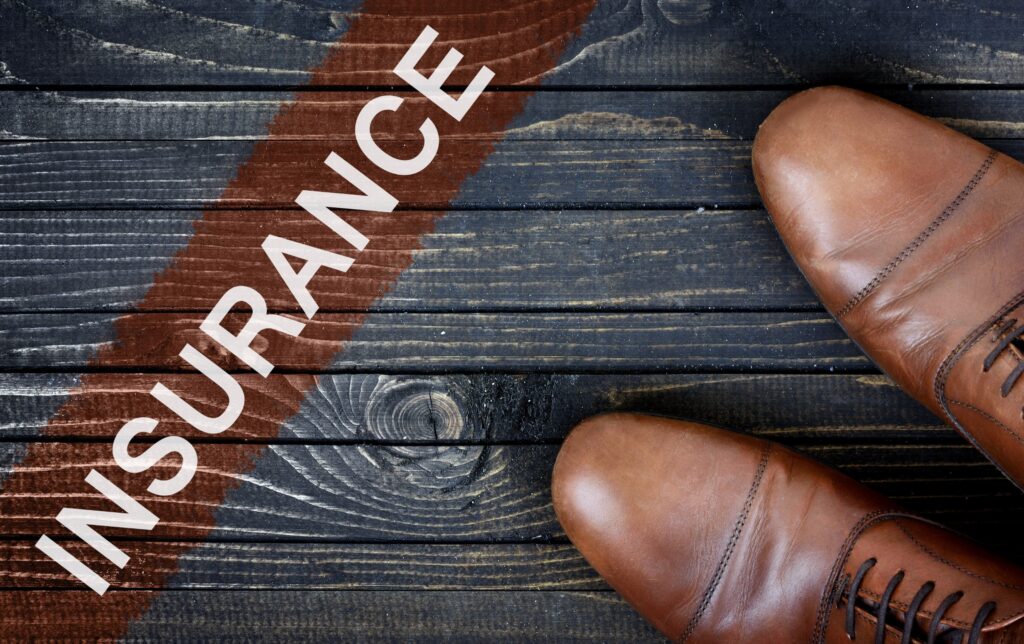The word "Insurance" written on a banner on the floor with someone's shoes in the corner of the image
