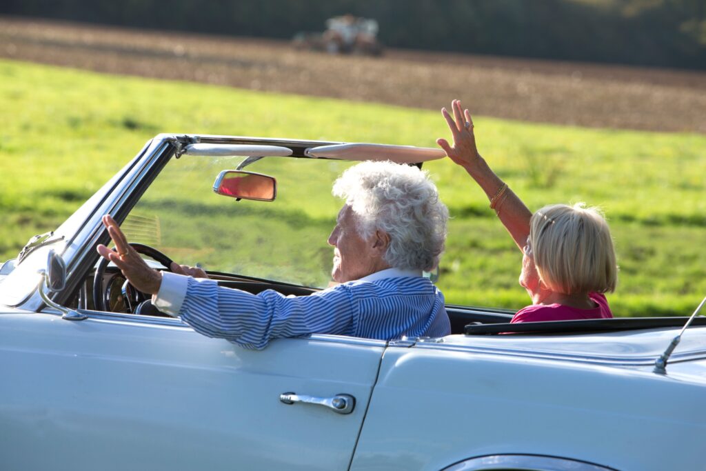 Elderly couple driving a light blue convertible